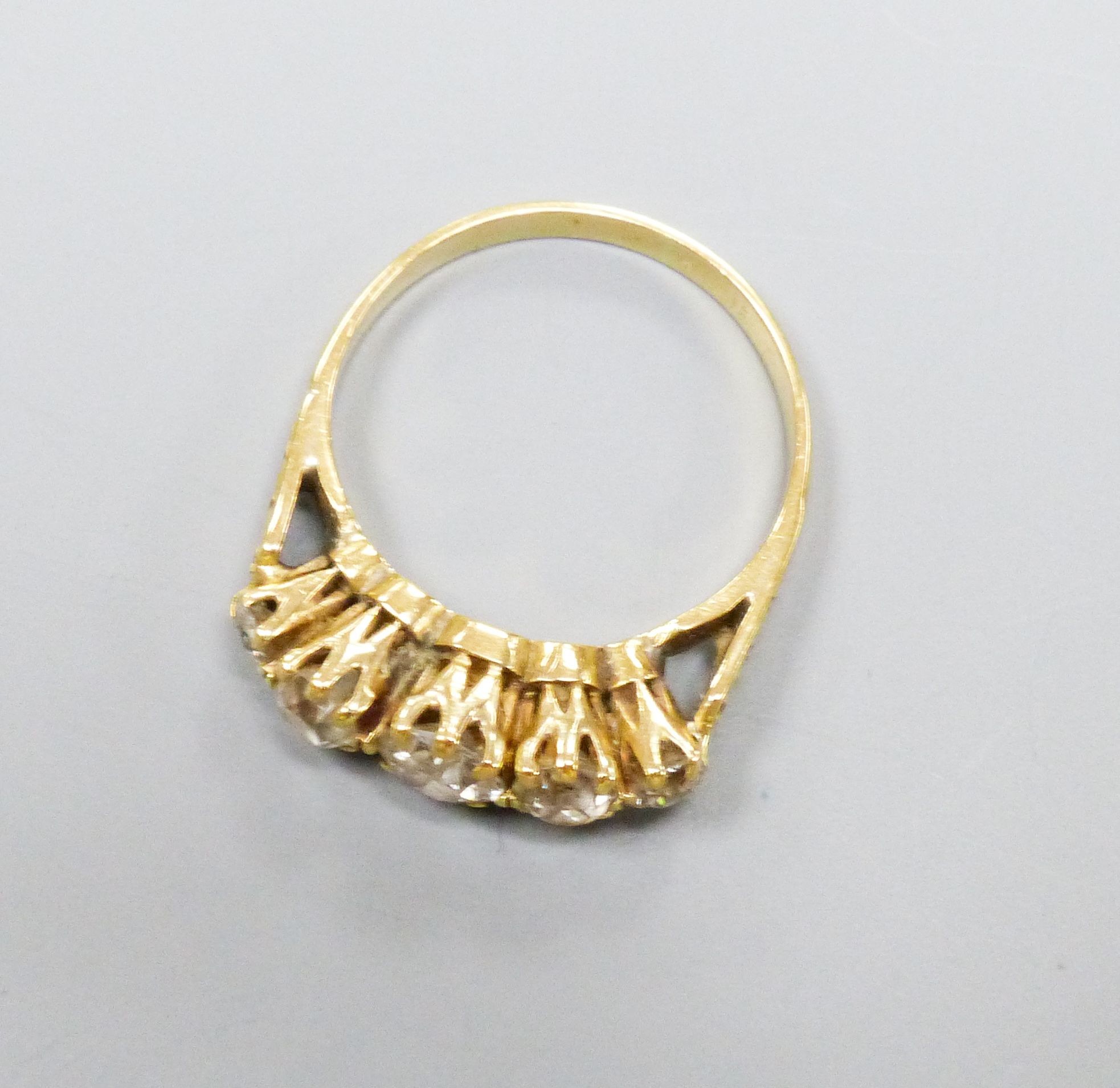 A five-stone diamond ring, yellow metal setting, claw-set with carved shoulders, size N, gross 3 grams.